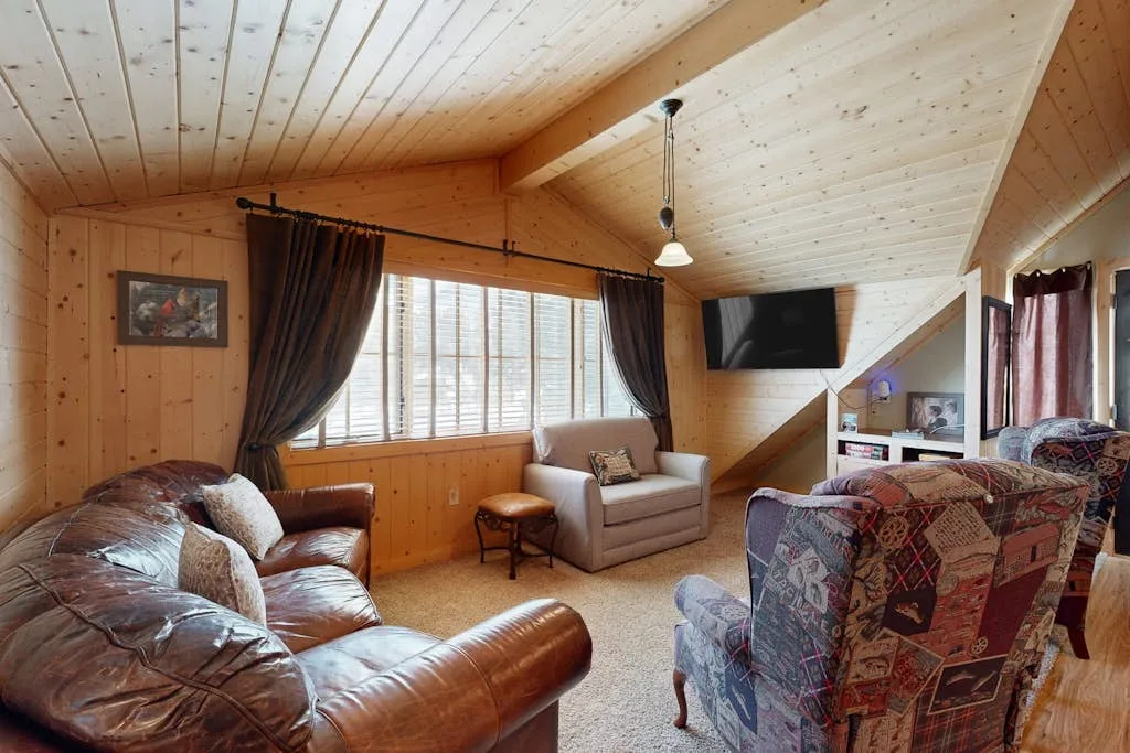 Una sala de estar revestida de madera con asientos dispuestos frente a un televisor.