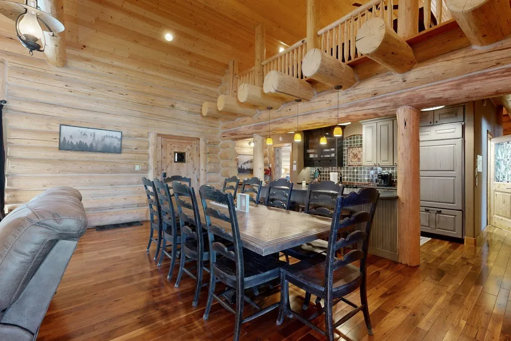 Comedor revestido de madera con una mesa larga y una encimera de cocina.