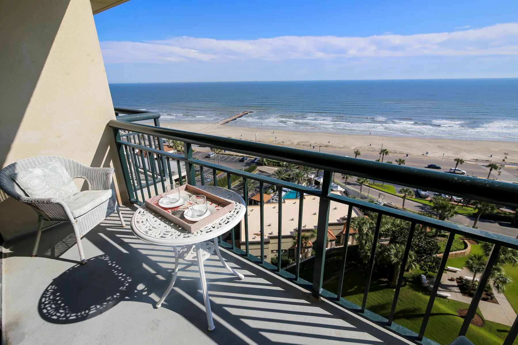 A balcony overlooks the ocean, with a small seating area and table.