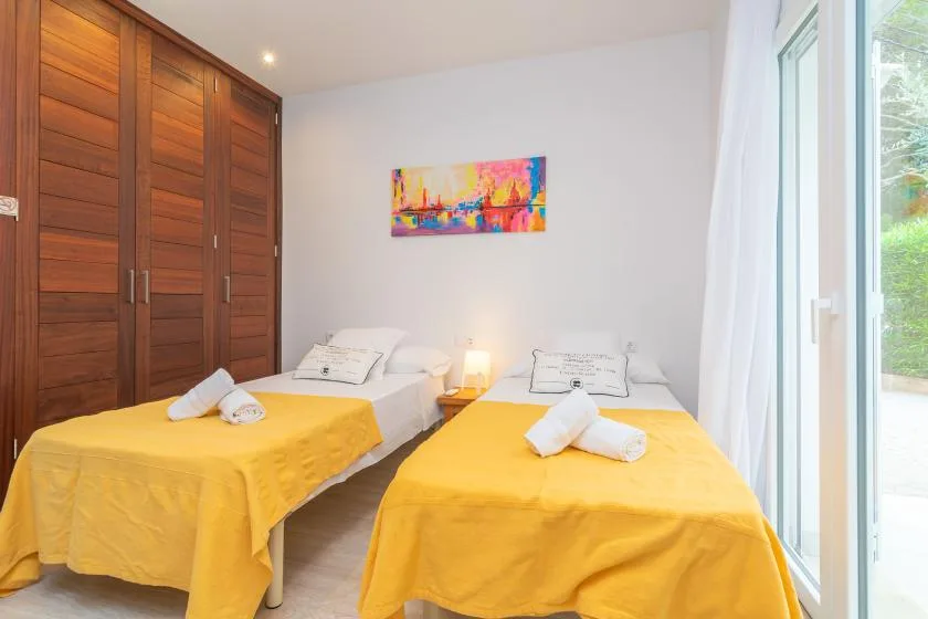 Un dormitorio con dos camas cubiertas con colchas amarillas junto a una ventana grande.