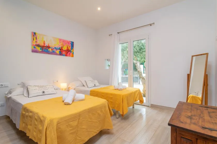 Un dormitorio luminoso con dos camas cubiertas de amarillo y una puerta de cristal.