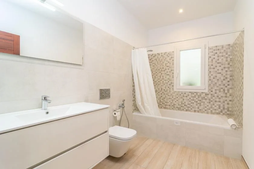 Un baño luminoso con bañera, cortina de ducha, lavabo e inodoro.