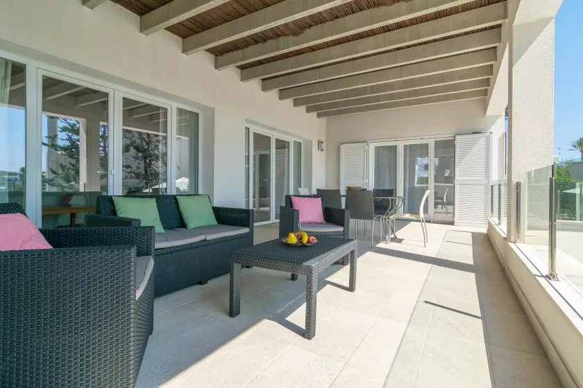 Un patio cubierto con asientos al aire libre y puertas de vidrio junto a la pared.