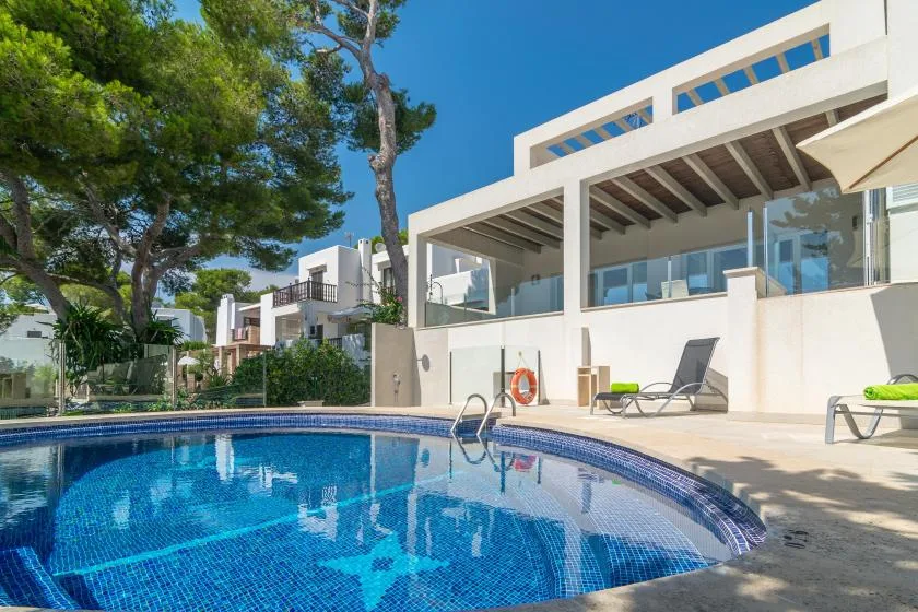 Una piscina curva está junto a un edificio moderno con asientos al aire libre.