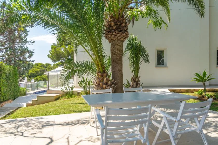 Zona de comedor al aire libre con una mesa y sillas junto a palmeras.