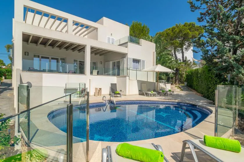 Una casa blanca moderna da a una piscina azul y una terraza.