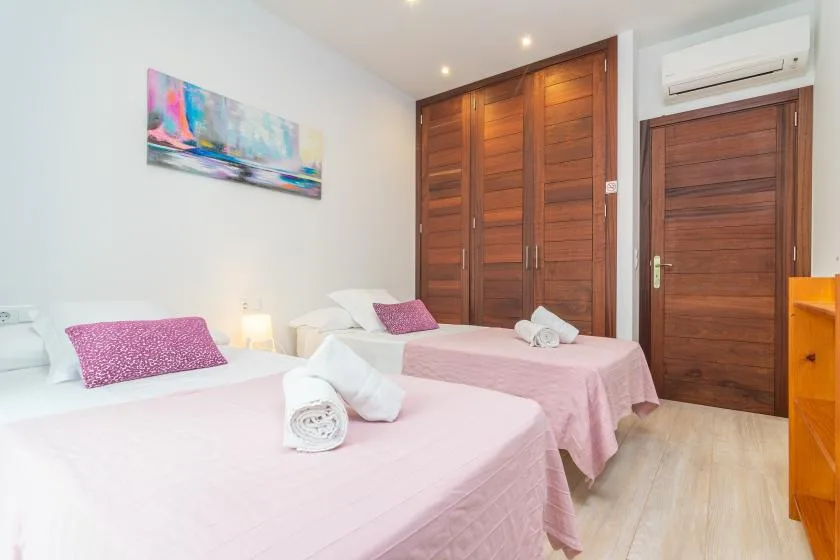 Un dormitorio con dos camas vestidas con ropa de cama rosa y puertas de madera.