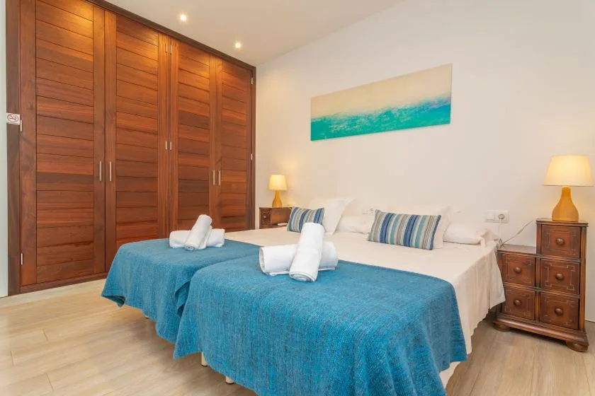 Un dormitorio con dos camas cubiertas con colchas azules y armarios de madera.