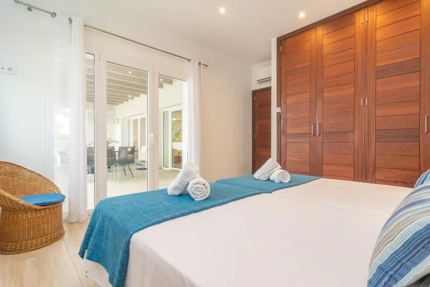 Un dormitorio con una cama cubierta de sábanas blancas y una manta azul.