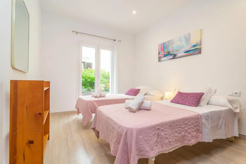 Un dormitorio luminoso con dos camas vestidas con ropa de cama rosa y blanca.