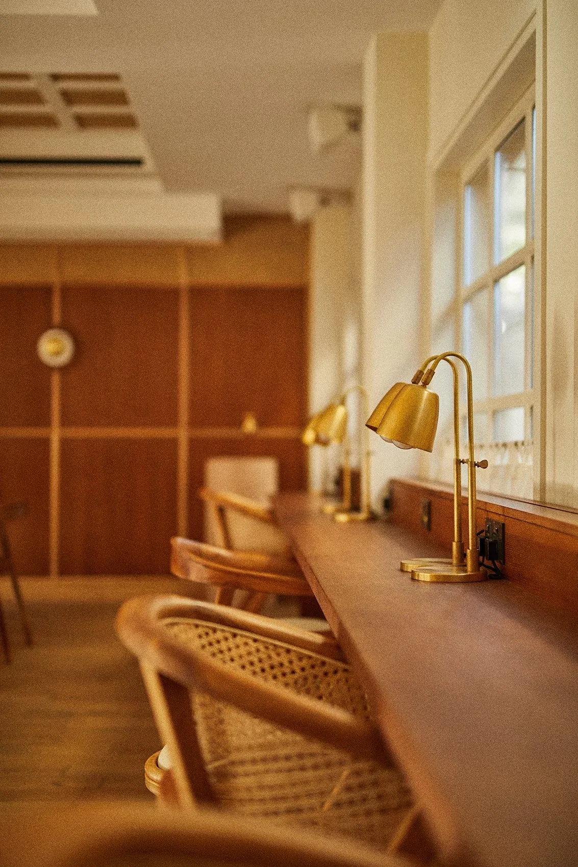 Interior con un mostrador de madera, lámparas de latón y sillas de mimbre.