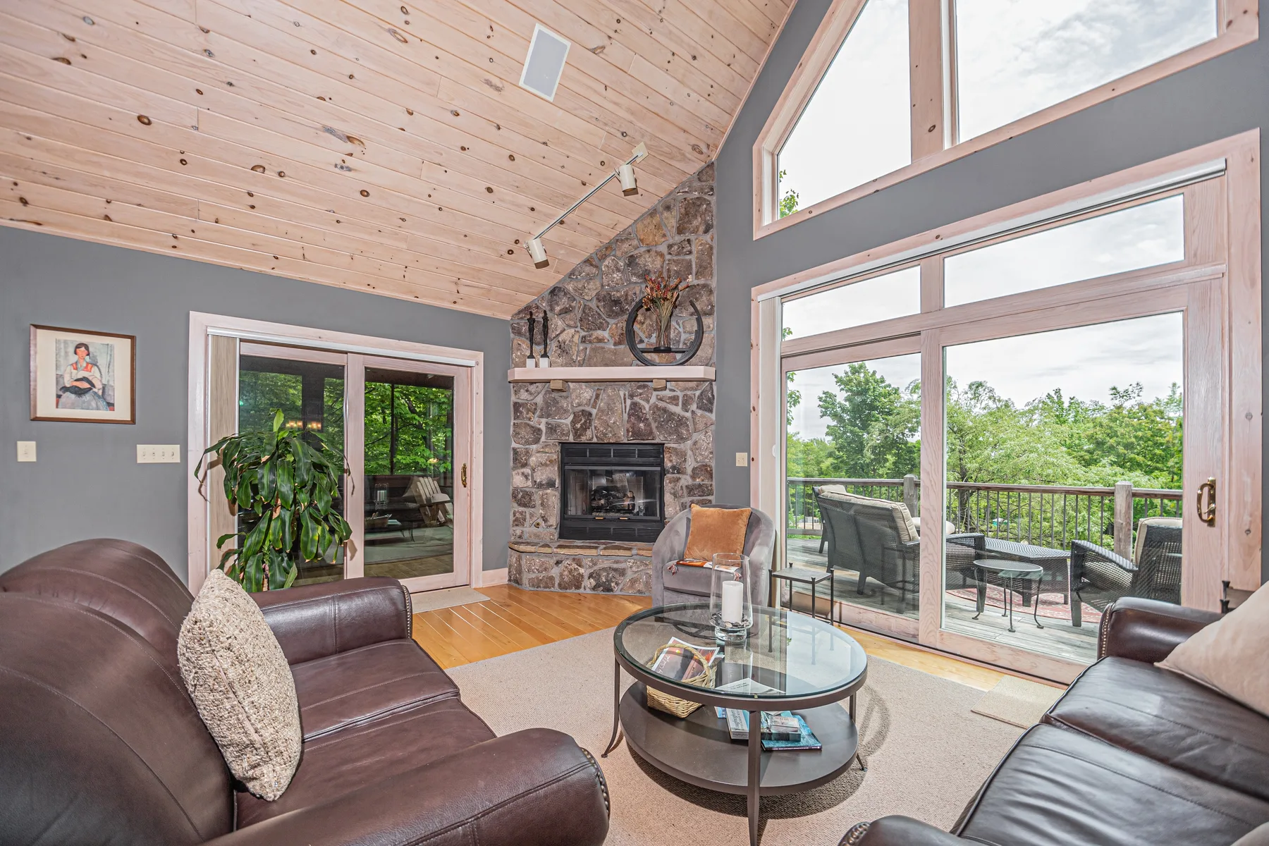 A living room with seating, a stone fireplace, and large windows.