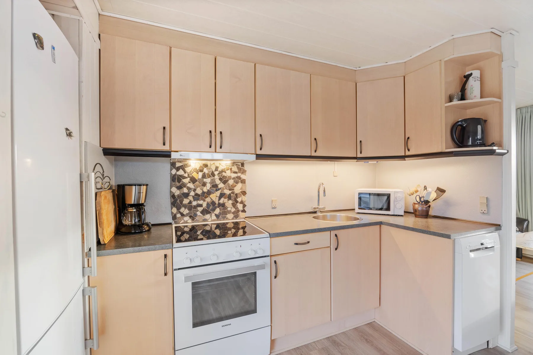 A bright kitchen with pale cabinets, a built-in oven, and a countertop.