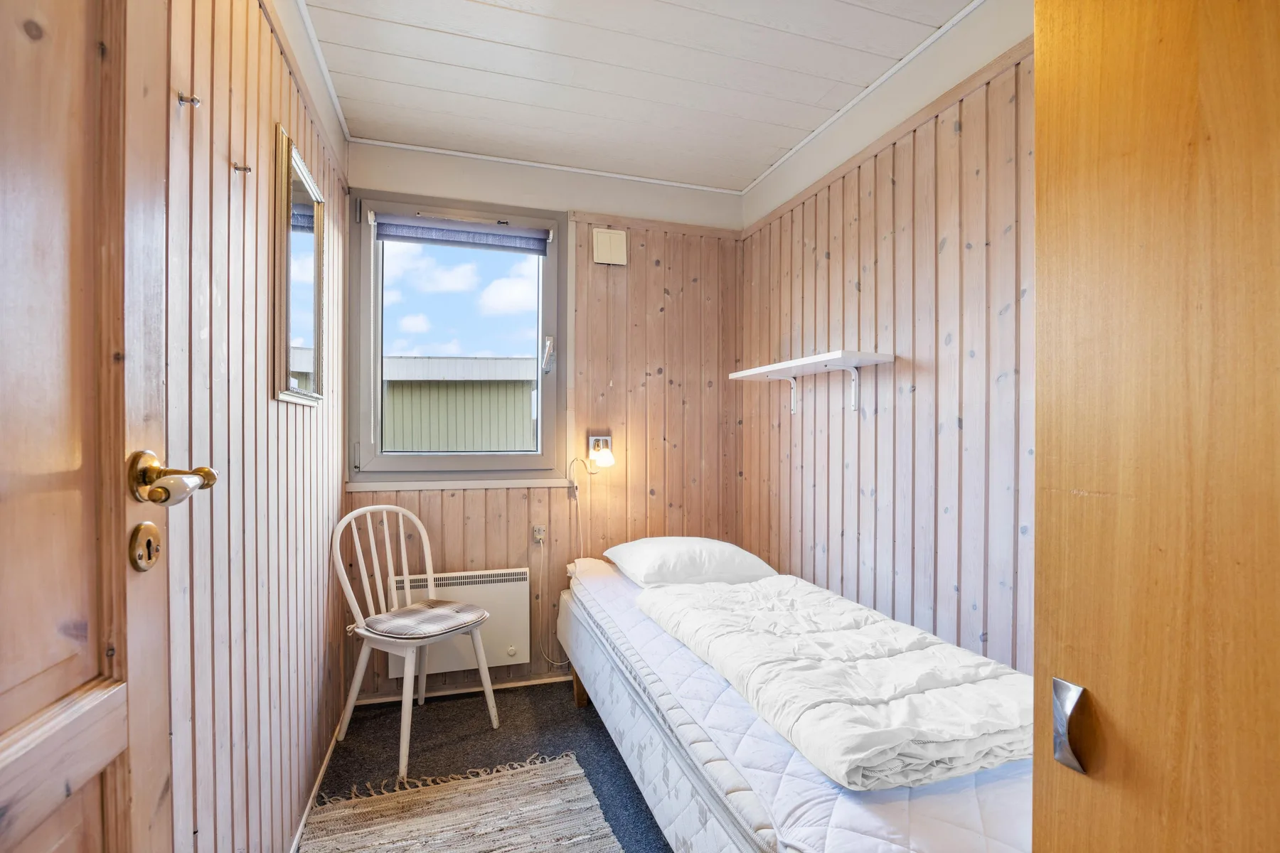 A narrow bedroom with a single bed and a window.