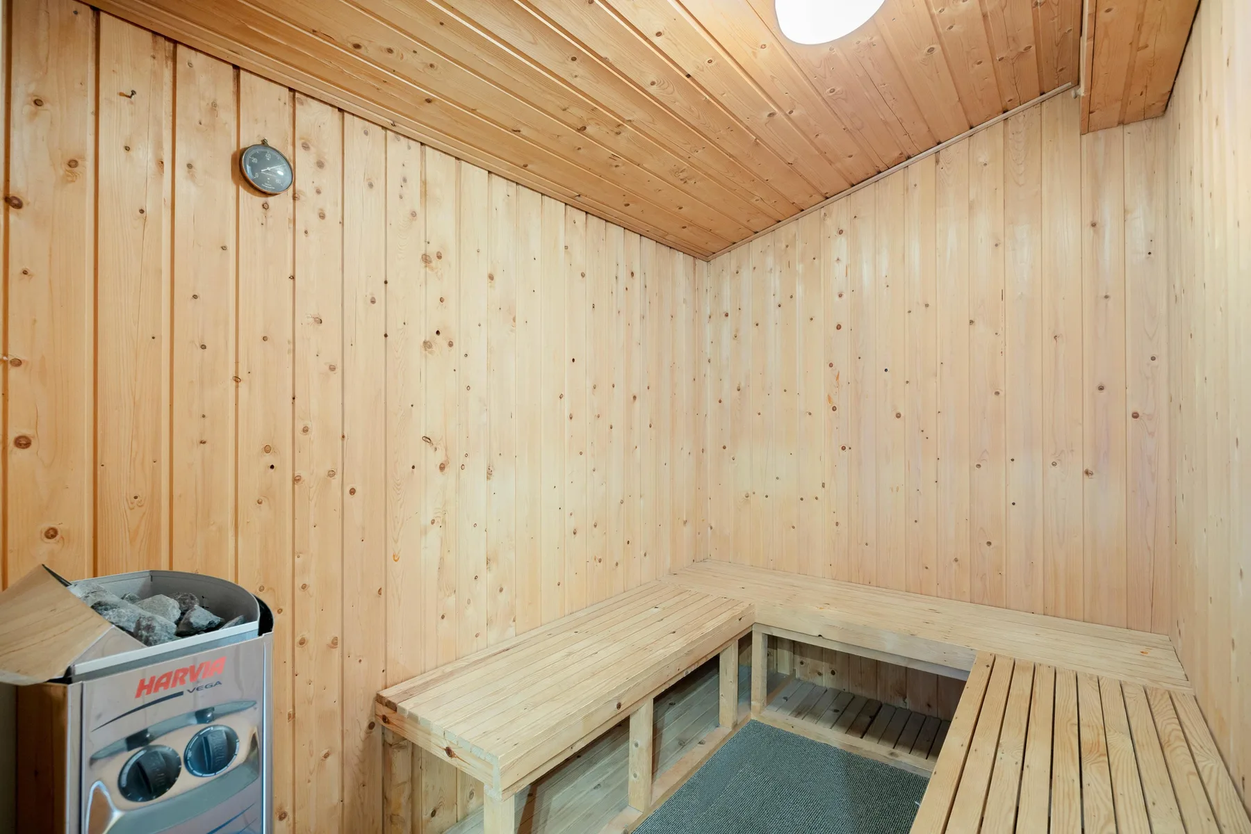 A wood-paneled sauna with tiered wooden seating and a small heater.