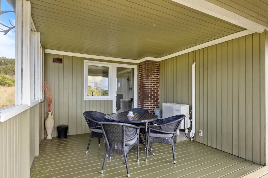 A covered patio with a round table and several chairs.