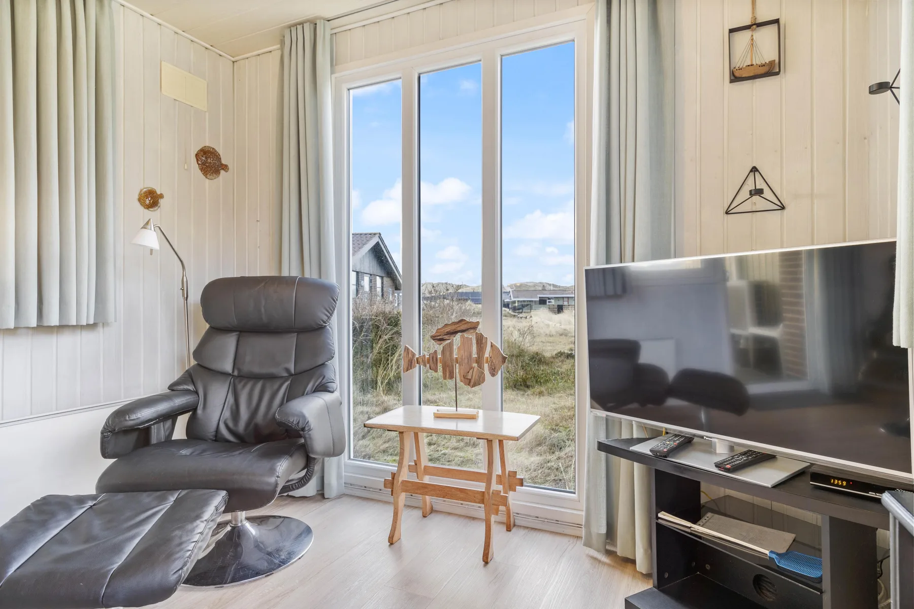 A bright living room with a recliner, television, and large glass doors.