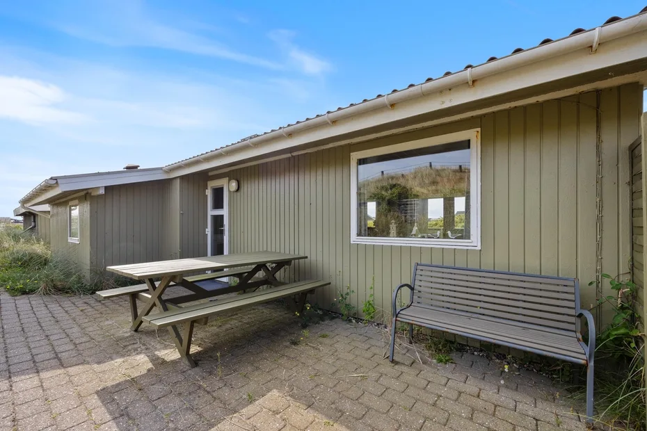 An outdoor patio beside a building, with a picnic table and bench.