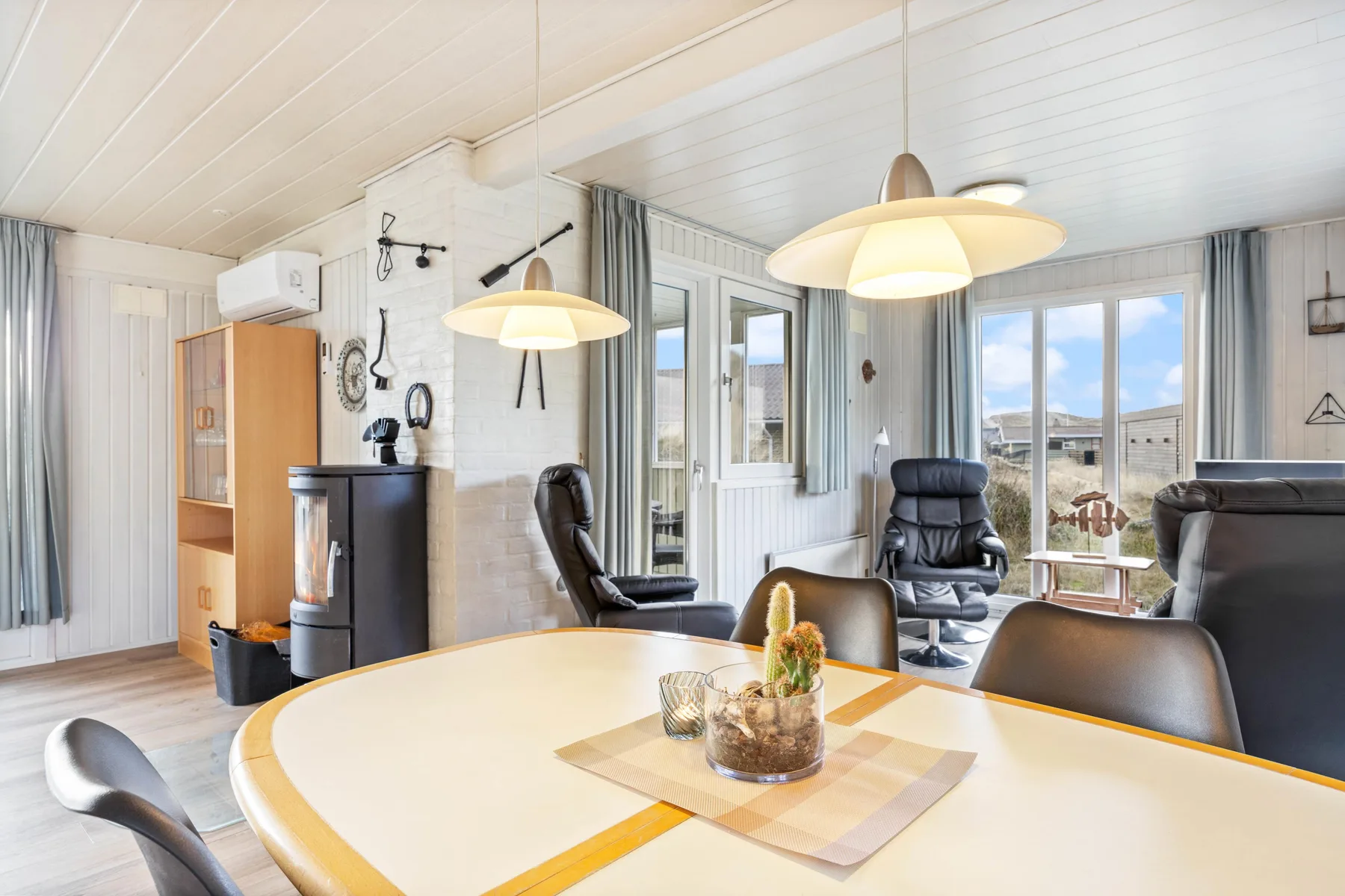 A dining and sitting area with a table, chairs, and large windows.