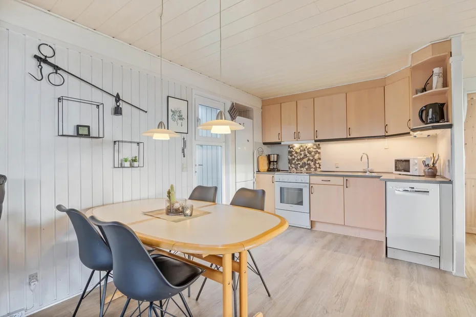 A dining area with a table and chairs beside a compact kitchen.