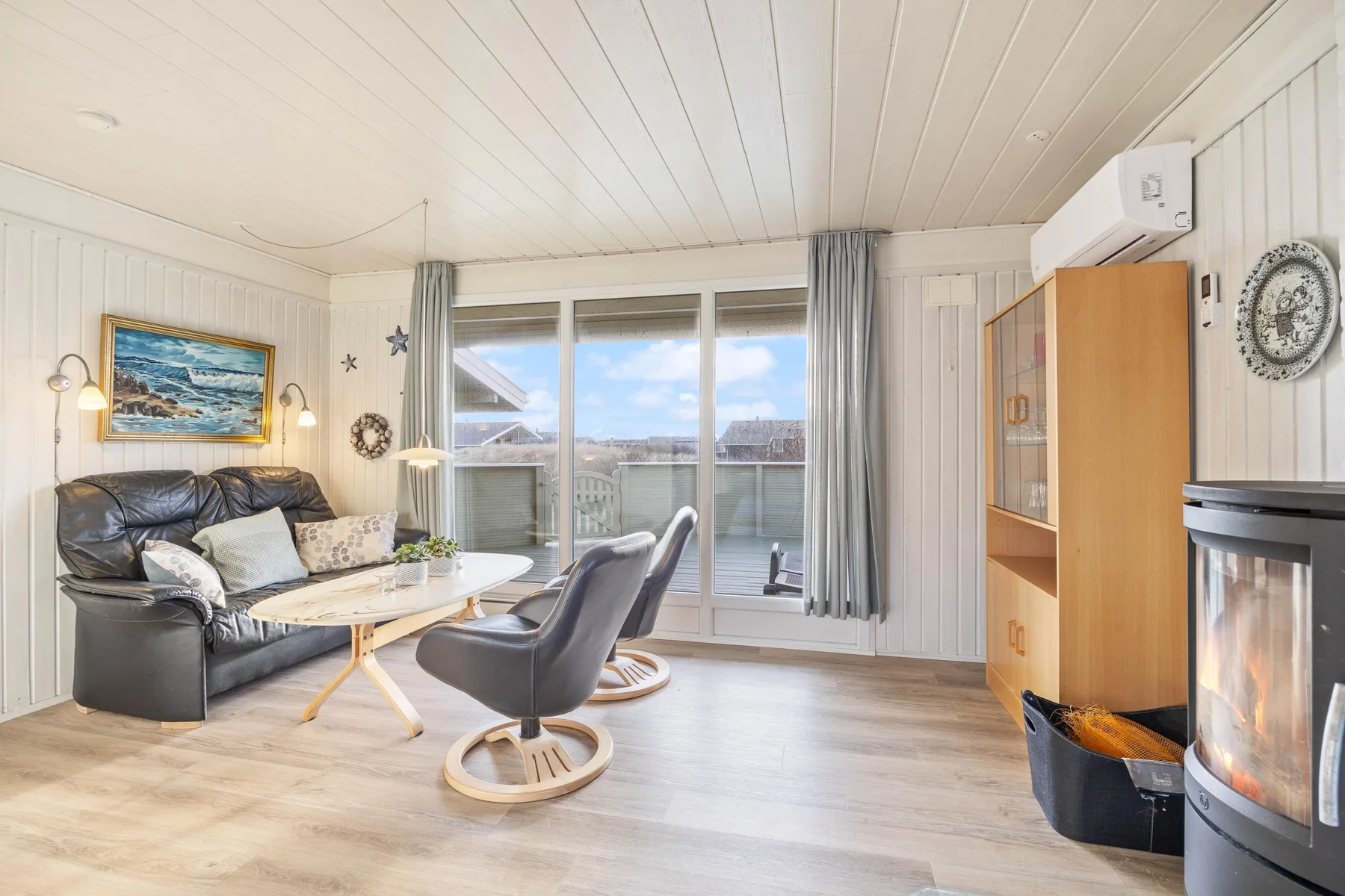 Living room with seating arranged around a coffee table and large windows.