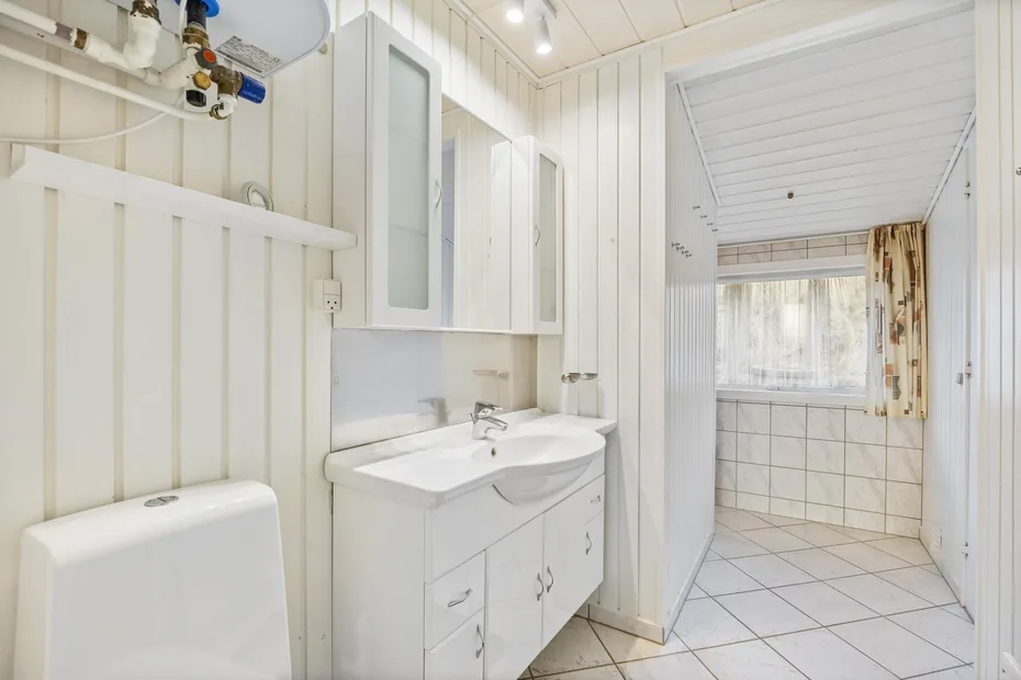 A bright bathroom with a sink, mirrored cabinet, and tiled shower area.