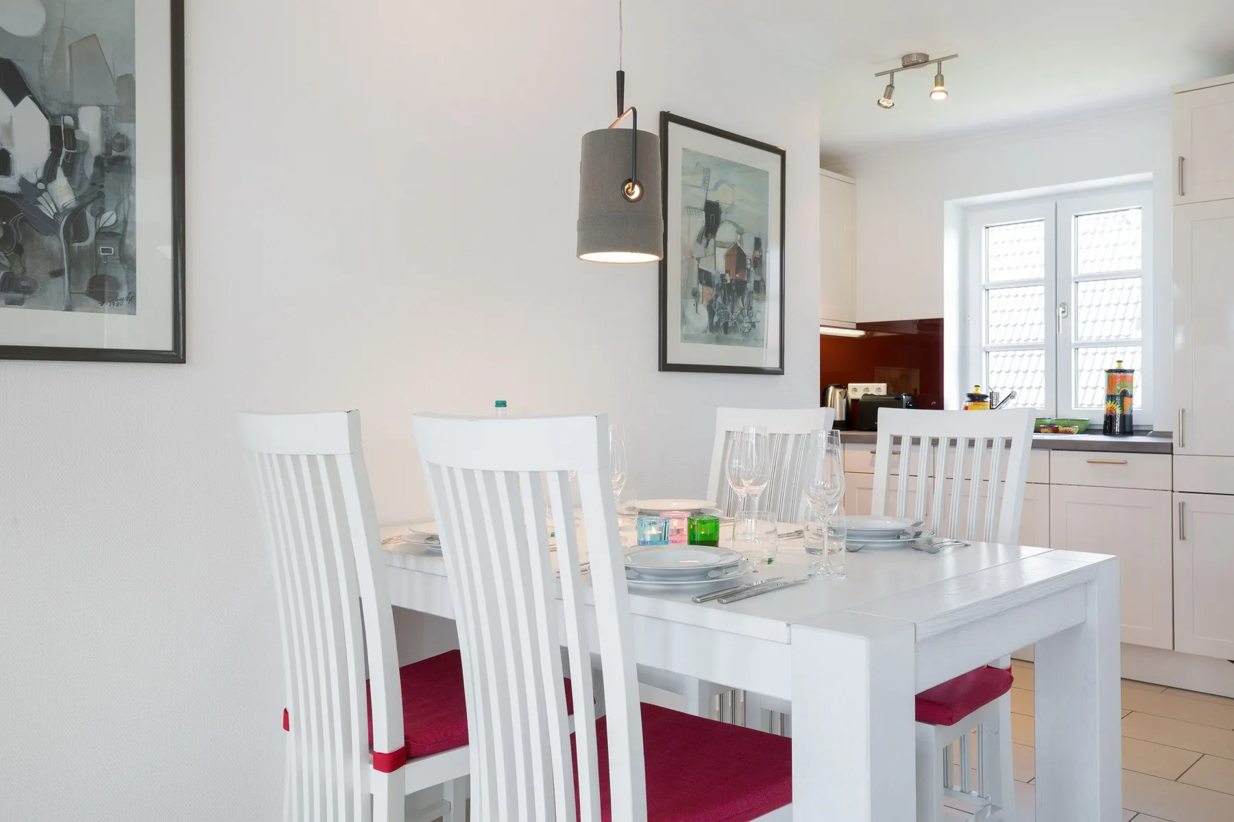 Un comedor luminoso con una mesa blanca y asientos junto a la cocina.