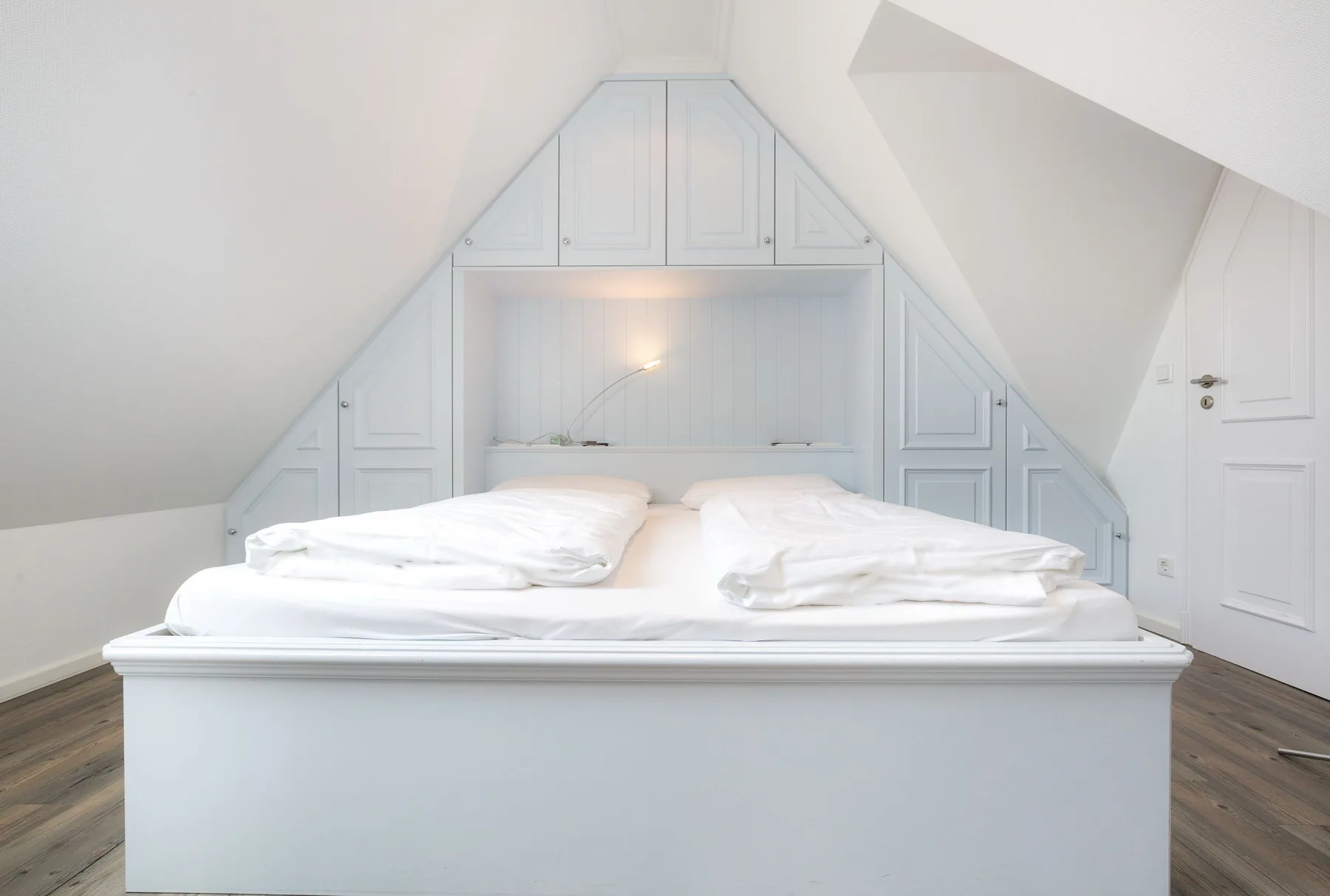 Un dormitorio con una cama bajo un techo inclinado.