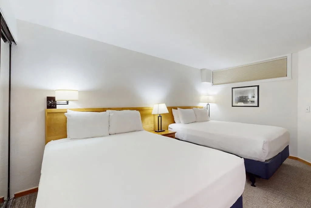 A bedroom with two beds and bedside lamps.