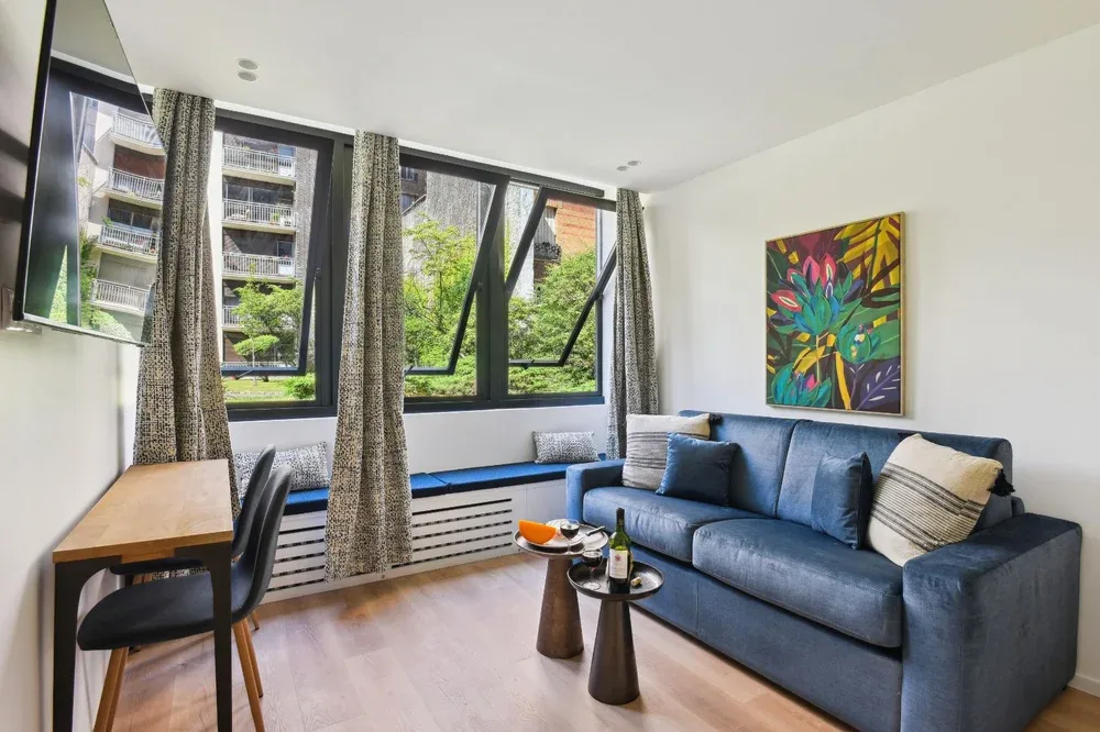 A bright living room with a blue sofa beside large windows.
