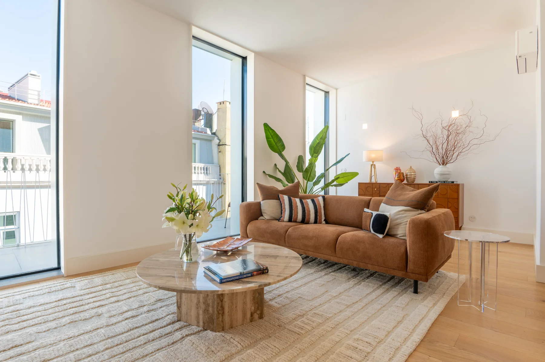A bright living room with a brown sofa, coffee table, and large windows.