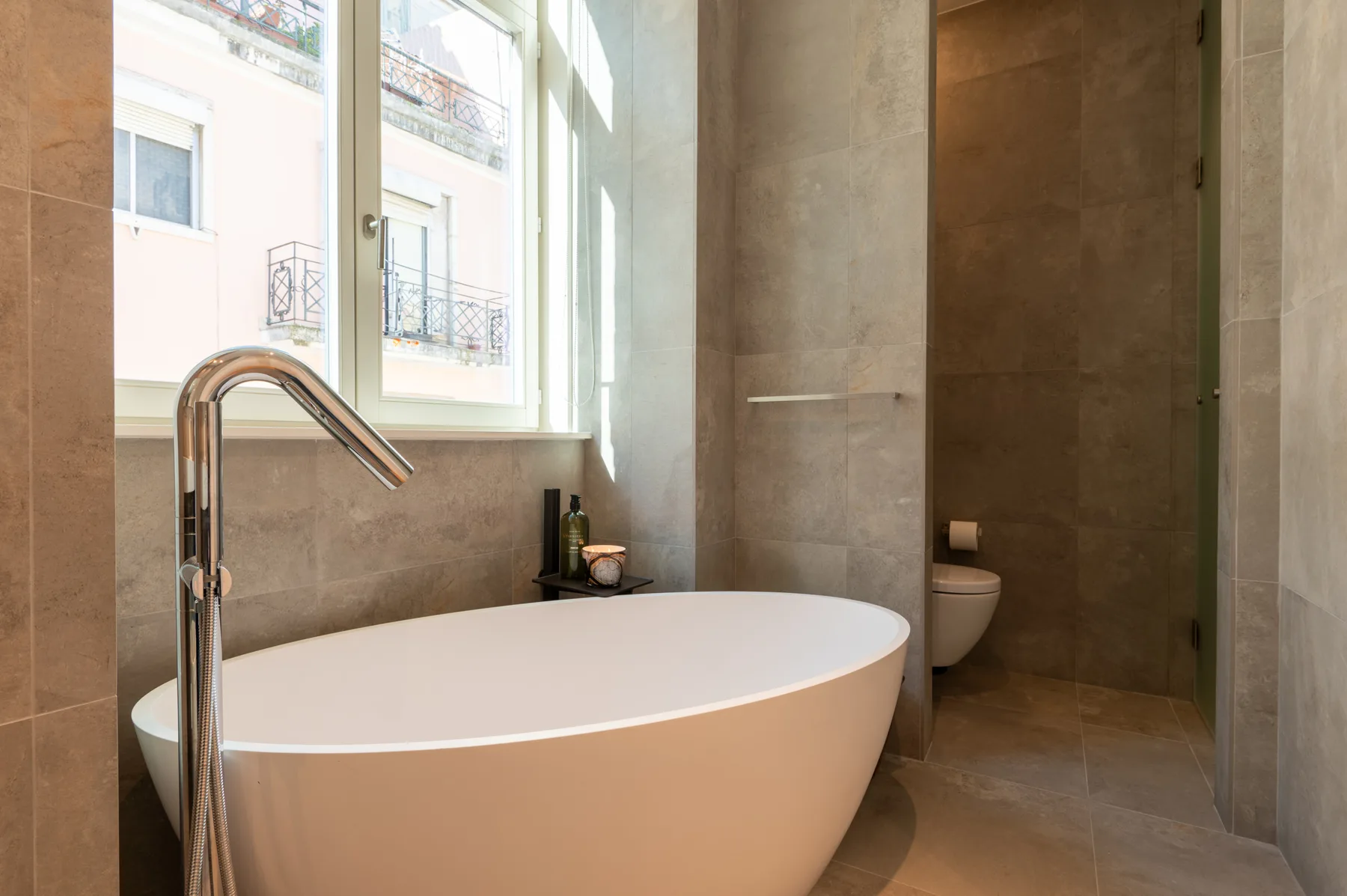 A bathroom with a freestanding bathtub beside a window.