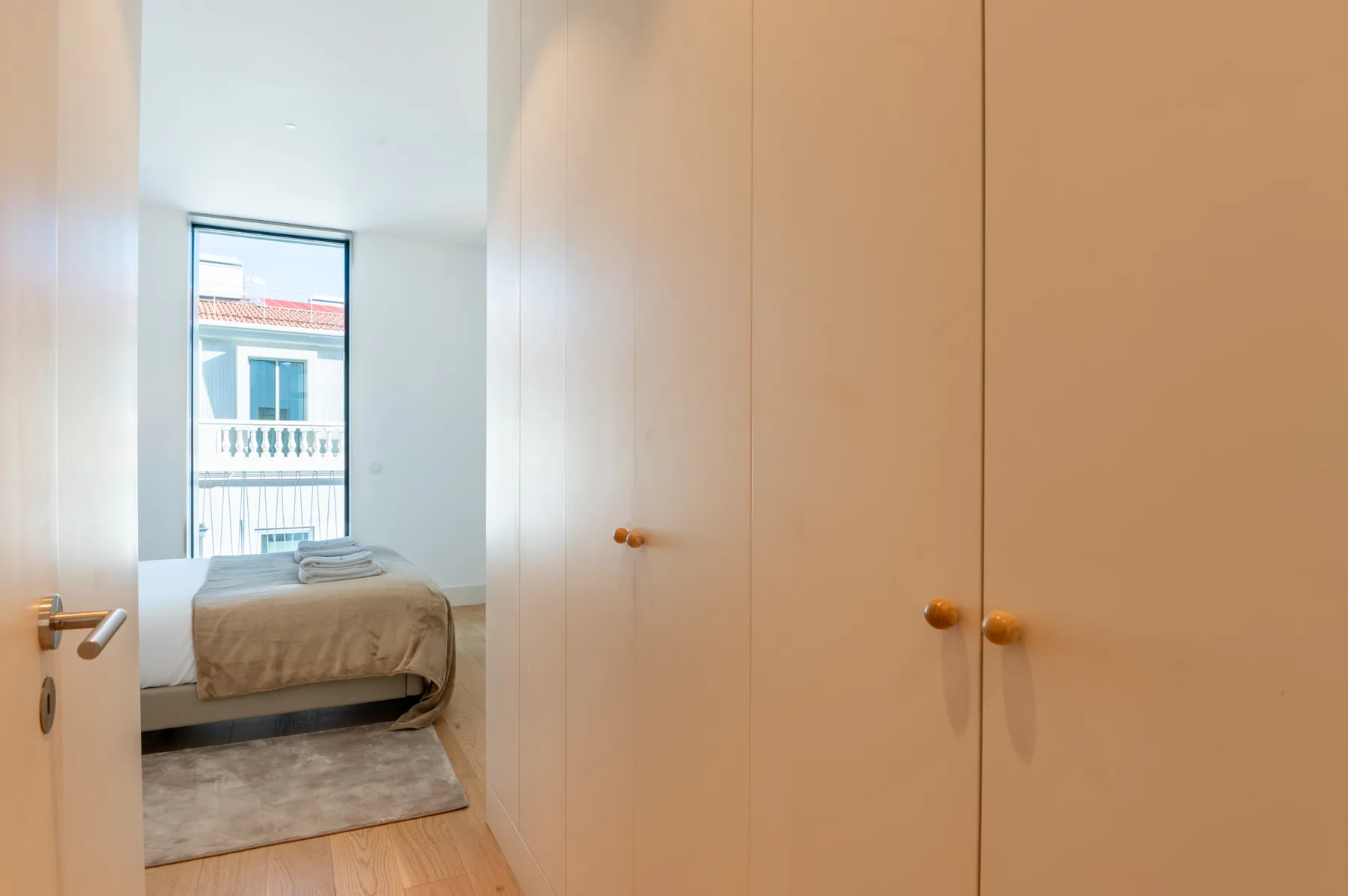 A bedroom with a bed beside a window and built-in wardrobes.