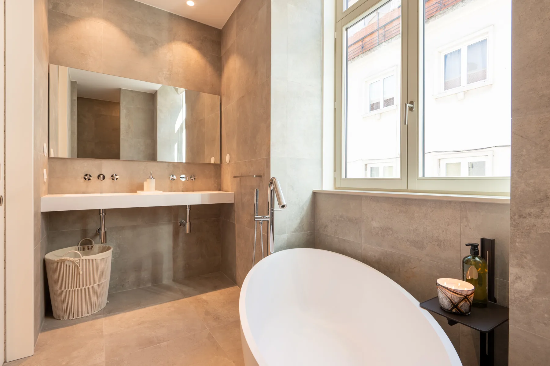 A bathroom with a bathtub, wide sink, and large window.