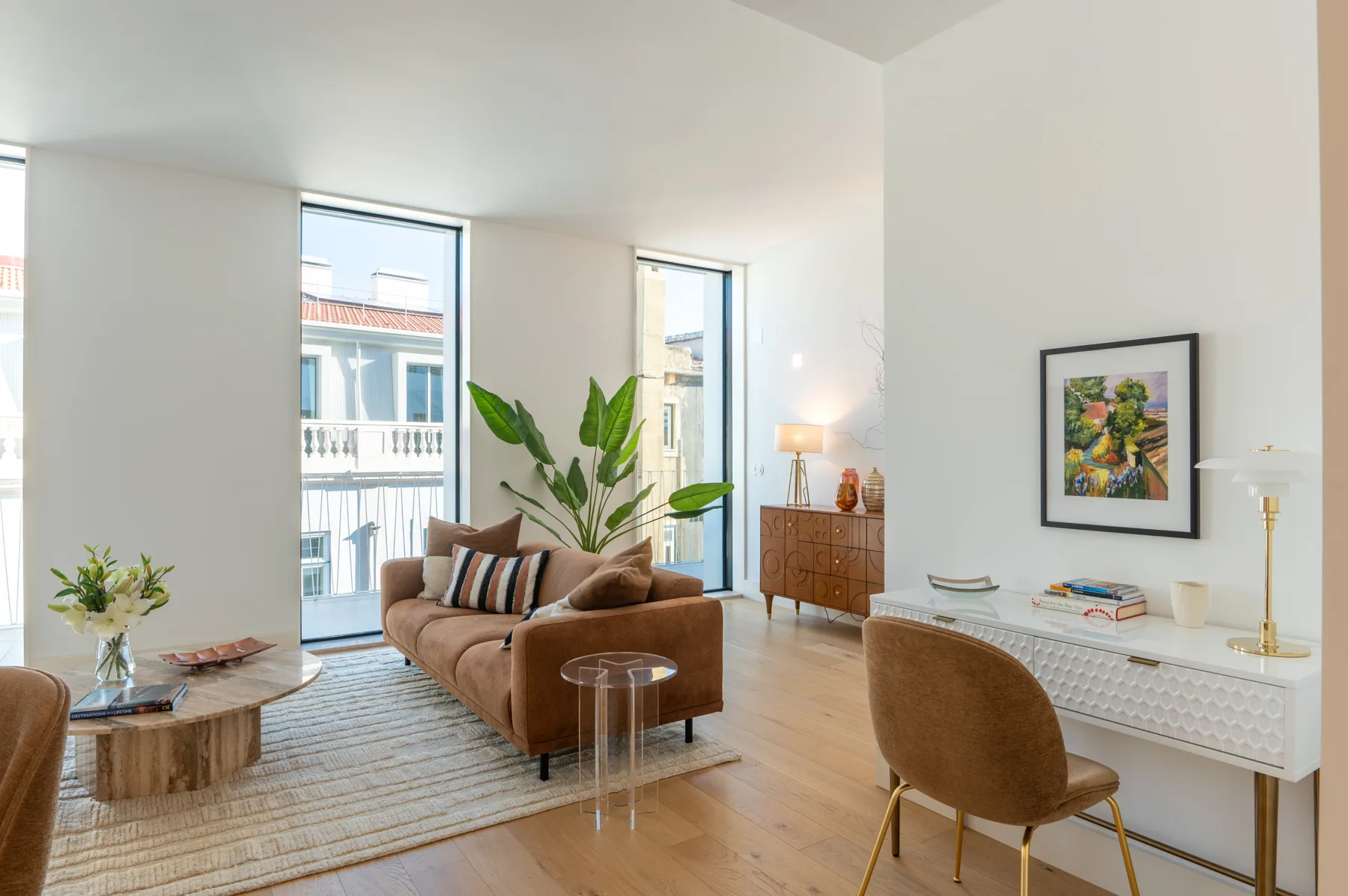 A bright living room with seating, a rug, and tall windows.