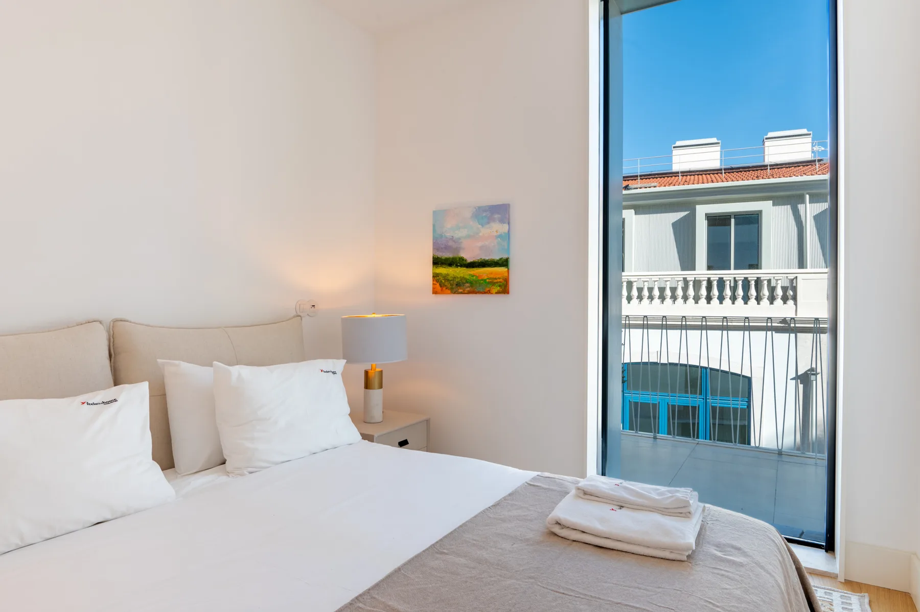 A bright bedroom with a neatly made bed beside a large window.