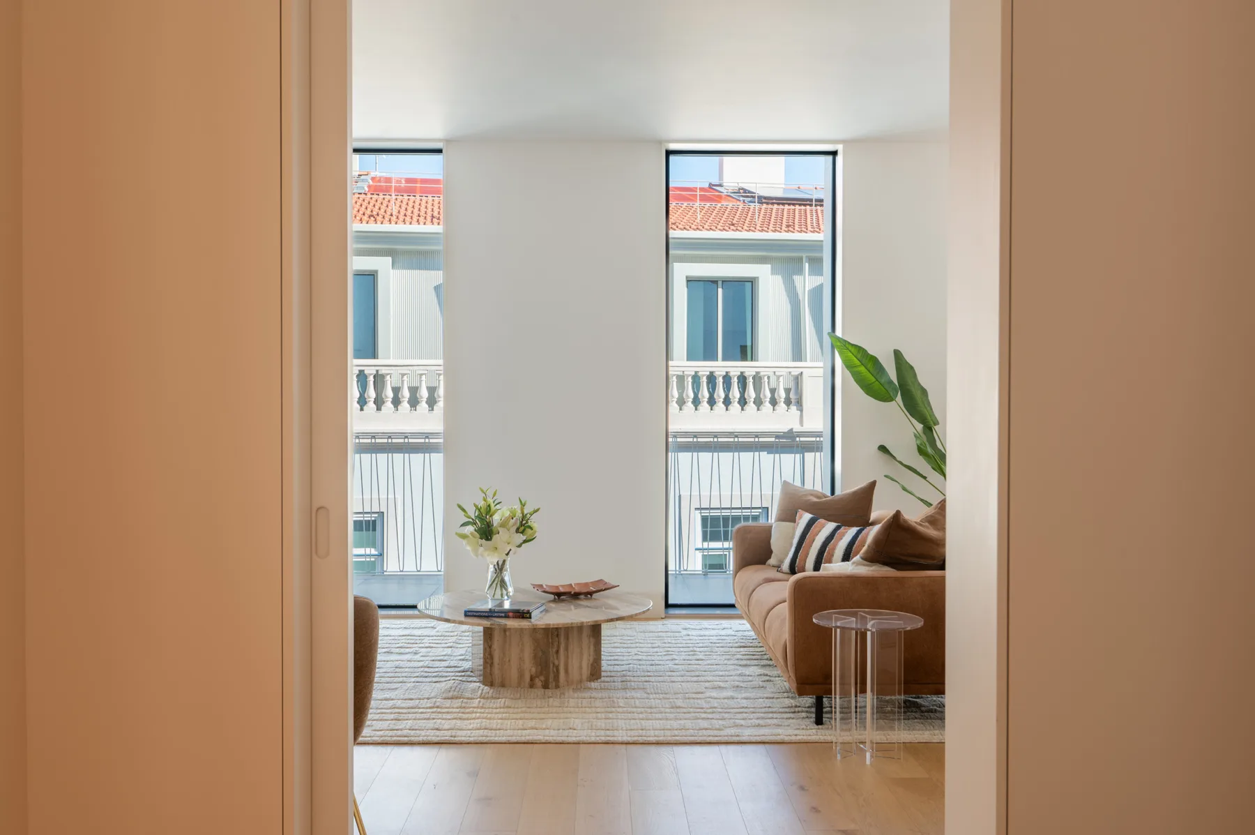 A living room with seating, a coffee table, and tall windows.
