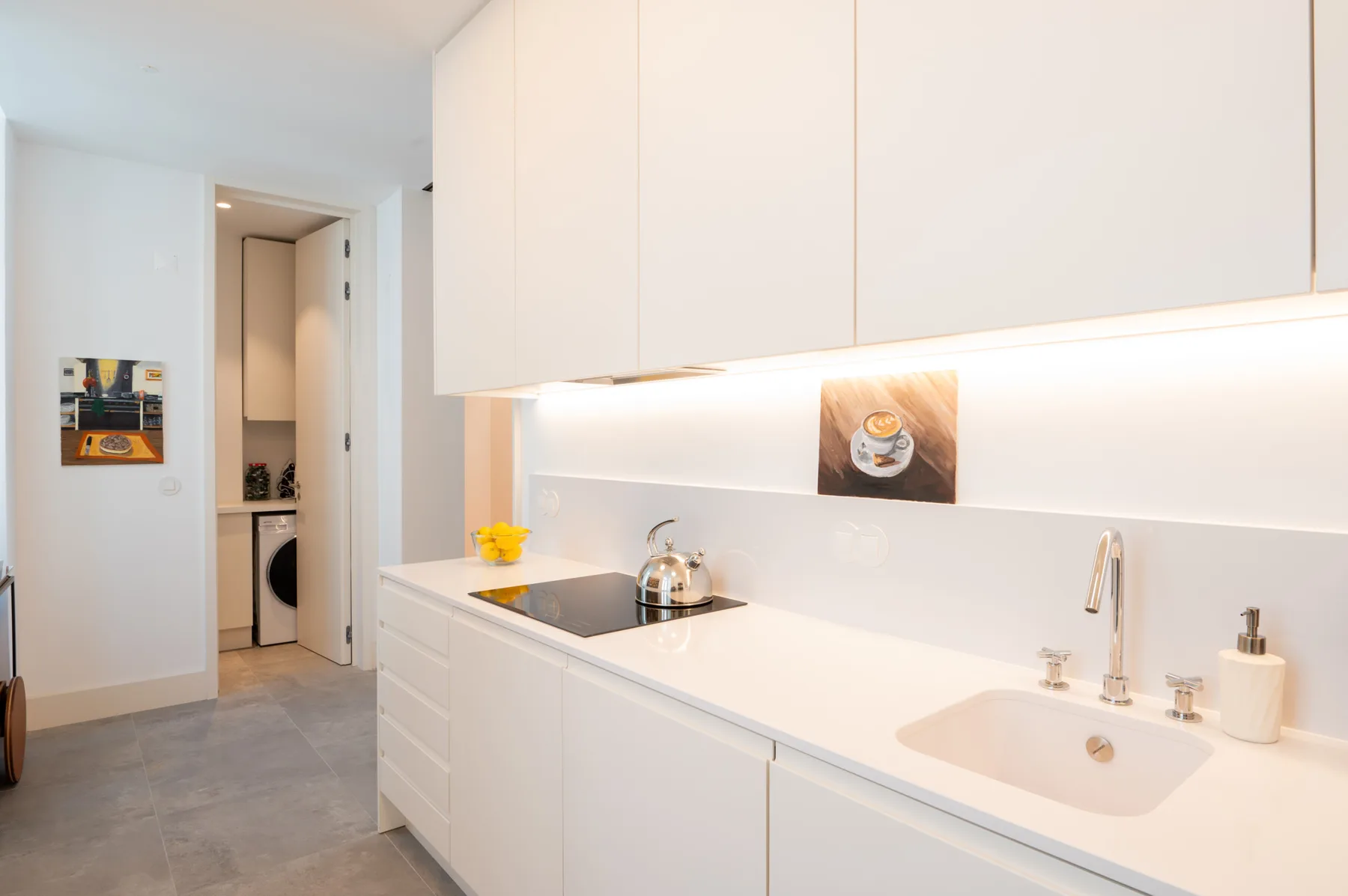A bright kitchen with white cabinets, a cooktop, and a sink.