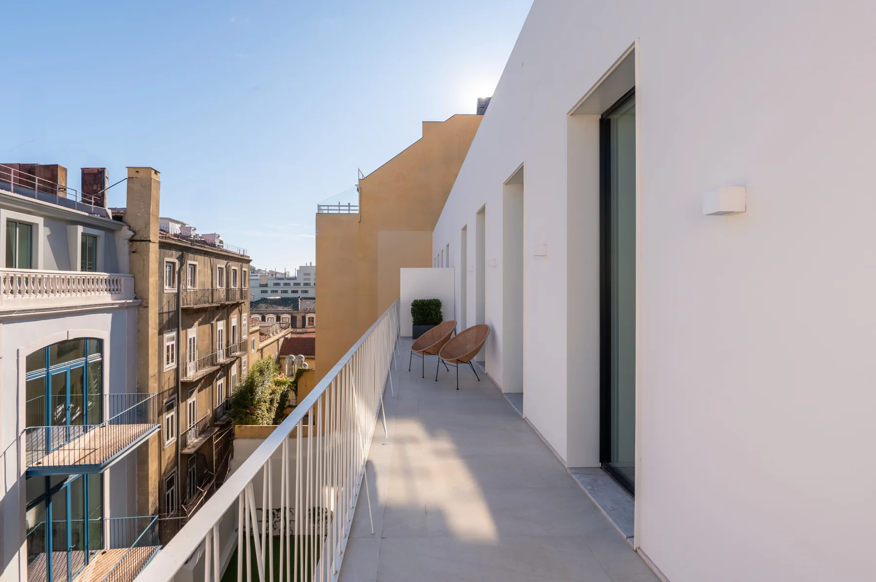 A balcony with outdoor seating overlooks neighboring buildings.