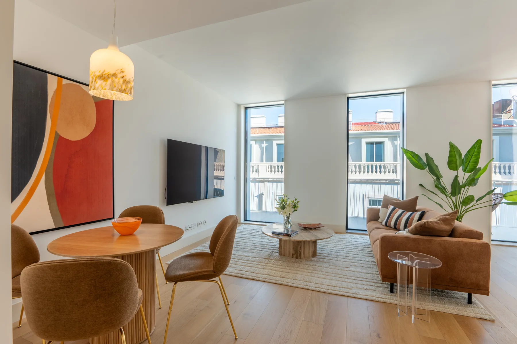 A bright living room with seating, a dining table, and large windows.