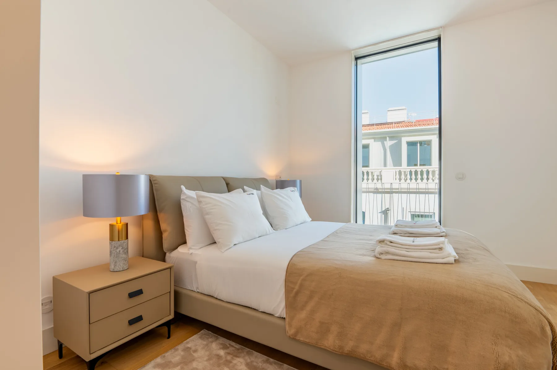 A bright bedroom with a bed and a tall window.