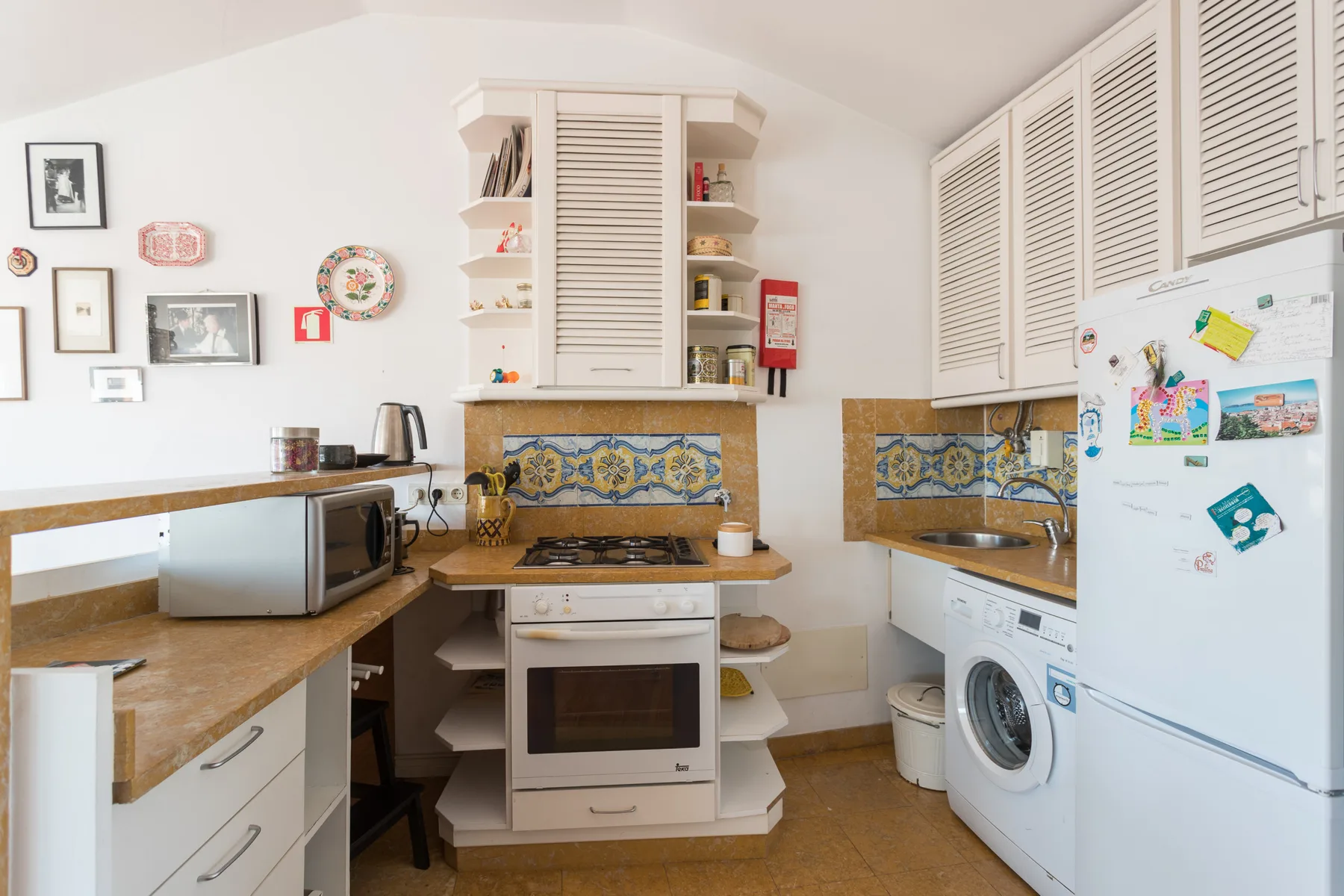 Una cocina compacta con encimeras de madera, un horno central y un refrigerador.