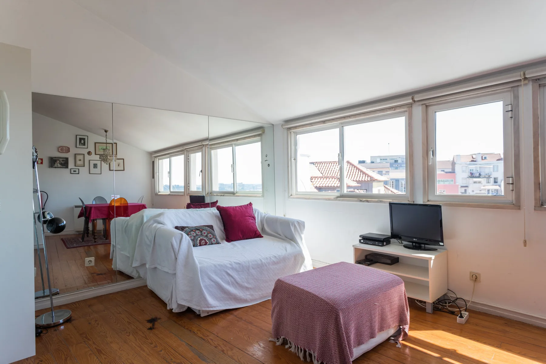 Una sala luminosa con un sofá blanco junto a grandes ventanas.