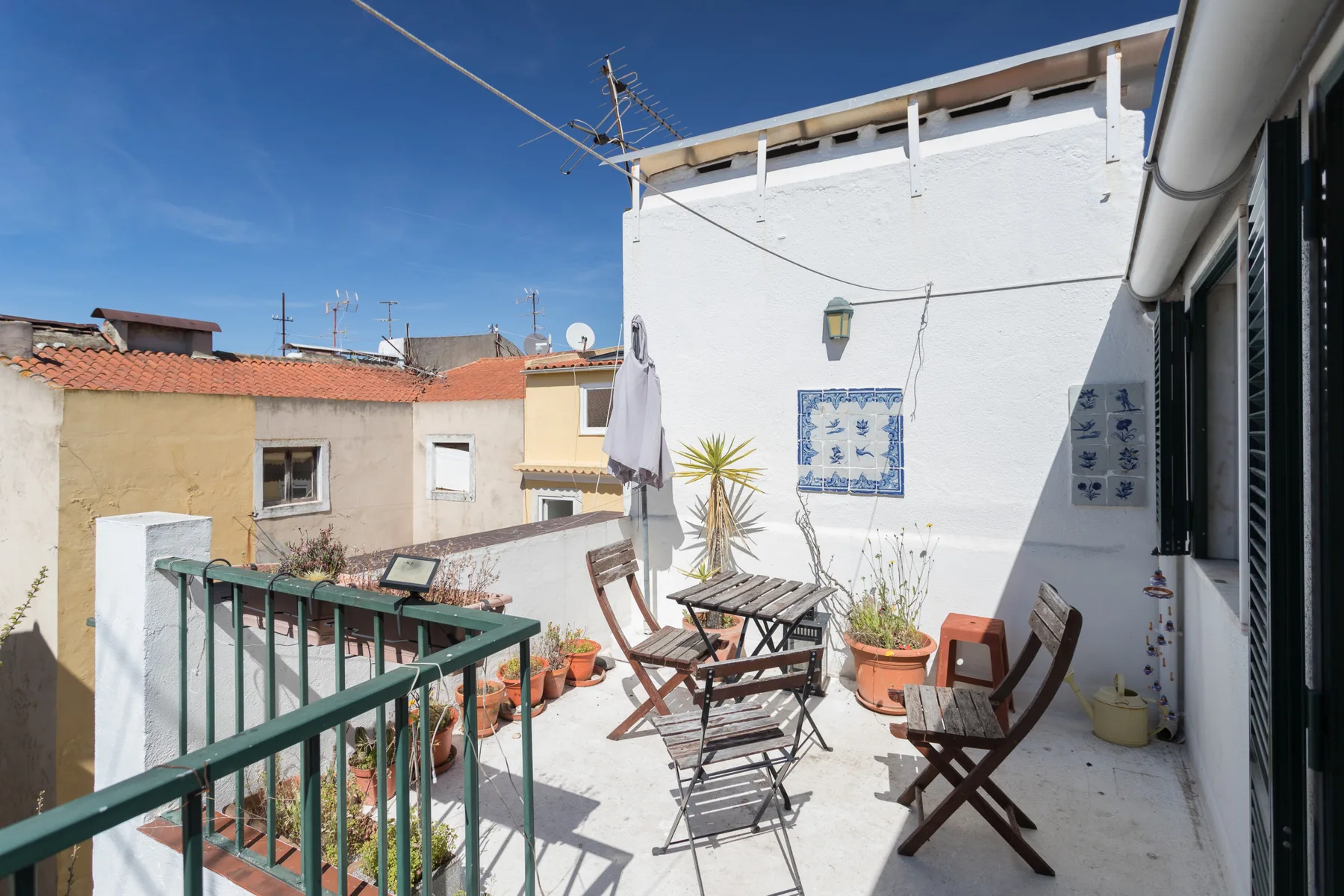 Una terraza soleada en la azotea con asientos al aire libre y plantas en macetas.