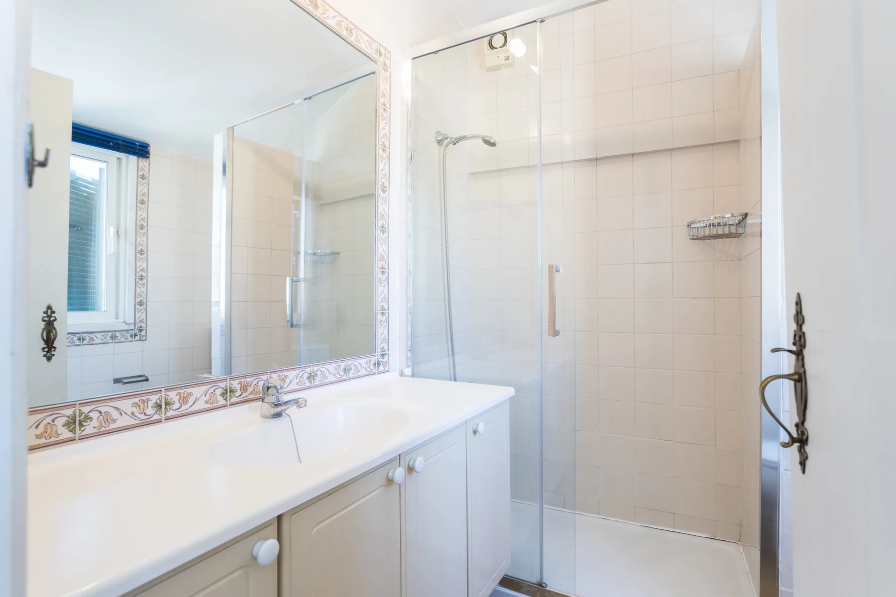 Un baño luminoso con lavabo, espejo y ducha de vidrio.