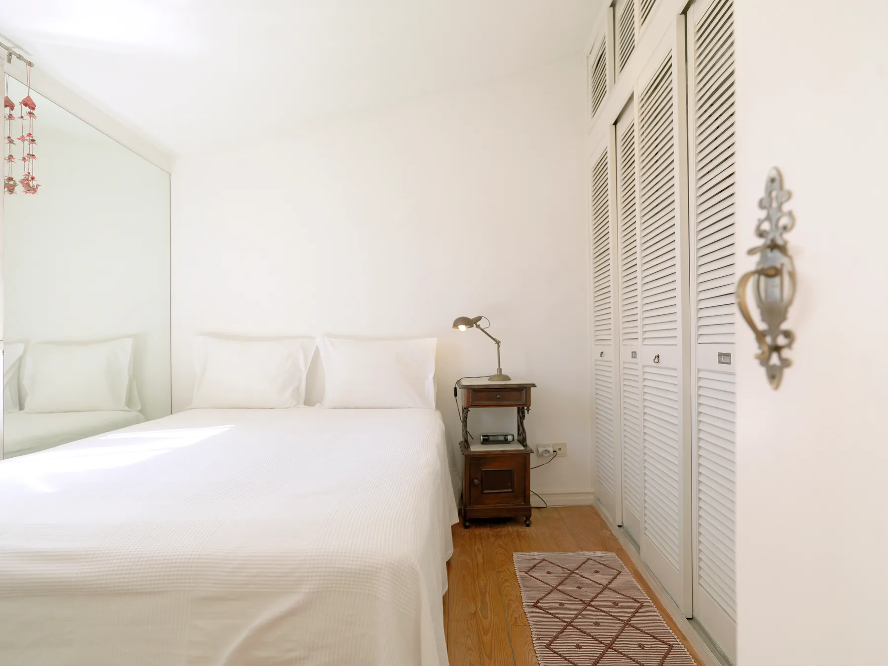 Un dormitorio luminoso con una cama bien tendida y una mesita de noche.