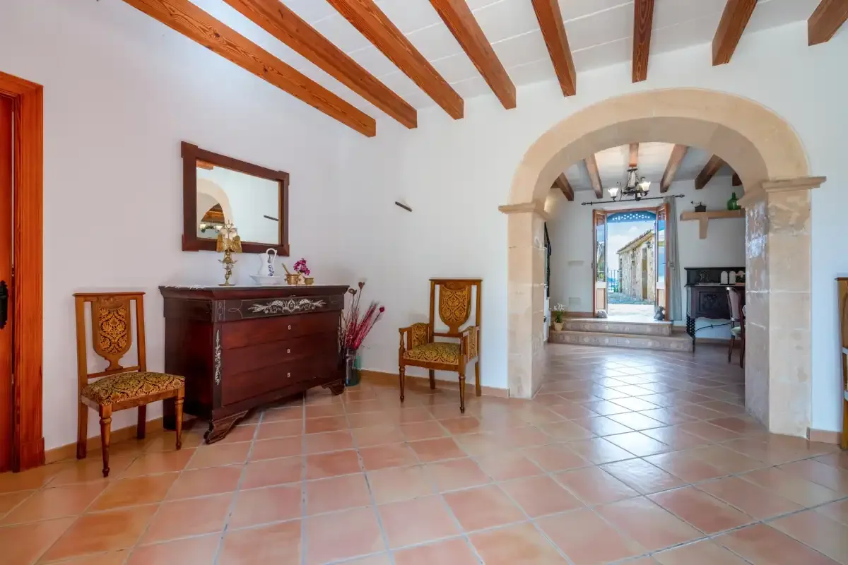 A tiled interior hallway with a stone archway and exposed wooden ceiling beams.