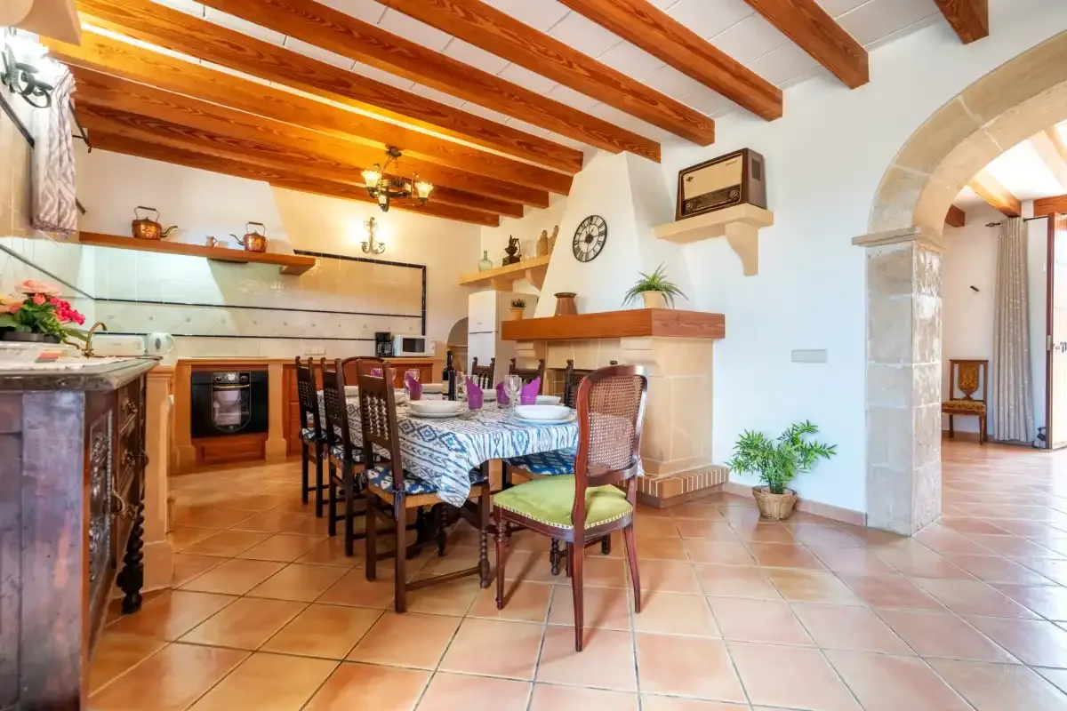 A dining area with a long table beside an open kitchen.