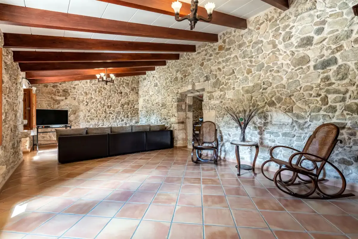 A stone-walled living room with dark seating and a tiled floor.