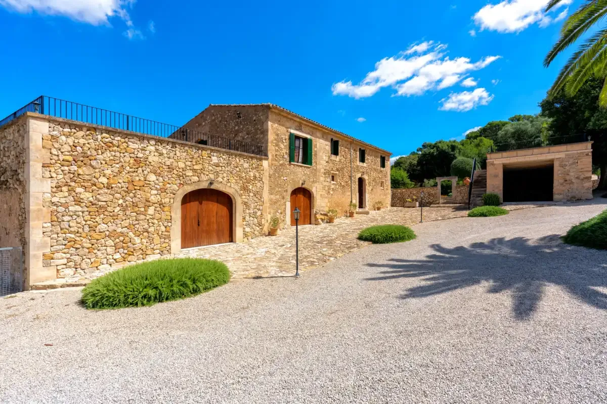 A stone building and paved courtyard sit beneath a bright blue sky.